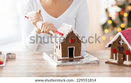 cooking, people, christmas and decoration concept - happy woman making gingerbread houses at home