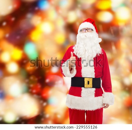 christmas, holidays, gesture and people concept- man in costume of santa claus showing thumbs up over red lights background