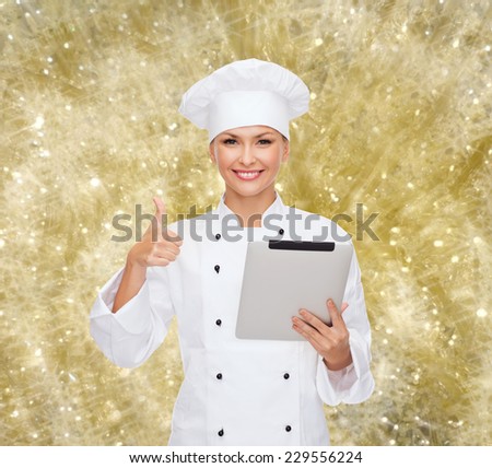 cooking, holidays, technology and people concept - smiling female chef, cook or baker with tablet pc computer showing thumbs up over yellow lights background