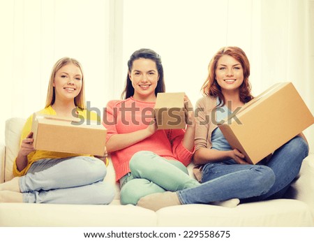 transportation, post and friendship concept - three smiling teenage girls with cardboard boxes at home