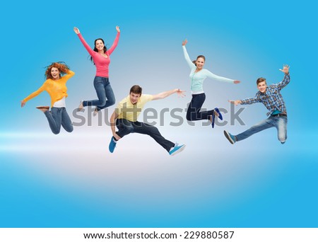 happiness, freedom, friendship, movement and people concept - group of smiling teenagers jumping in air over blue laser background