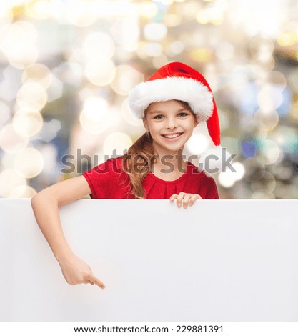 christmas, holidays, people, advertisement and sale concept - happy little girl in santa helper hat with blank white board over lights background
