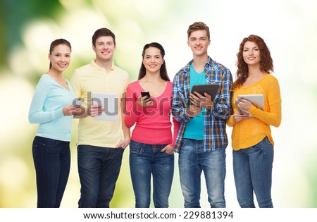 friendship, technology and people concept - group of smiling teenagers with smartphones and tablet pc computers over green background