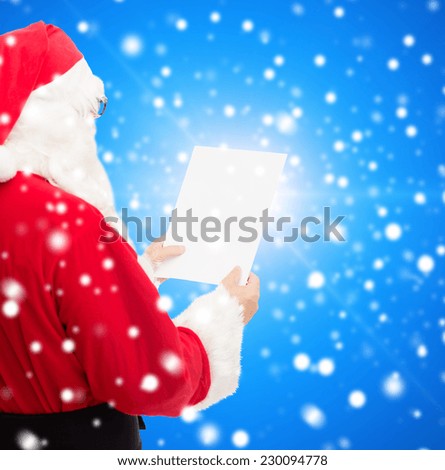 christmas, holidays and people concept - man in costume of santa claus reading letter over blue snowy background