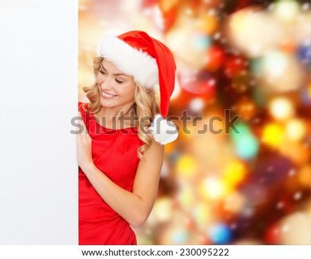 winter holidays, christmas, advertising and people concept - smiling young woman in santa helper hat with white blank billboard over red lights background