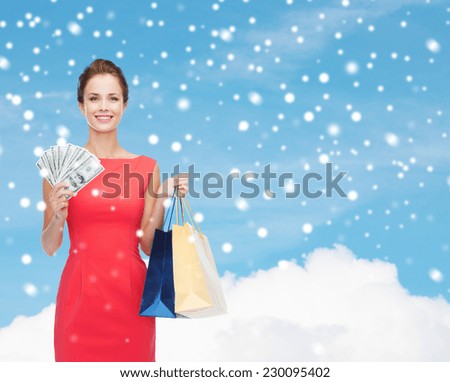 shopping, sale, christmas and holiday concept - smiling elegant woman in red dress with shopping bags and dollars over blue sky with cloud and snow background
