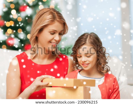 christmas, holidays, people and family concept - smiling mother and daughter opening gift box at home