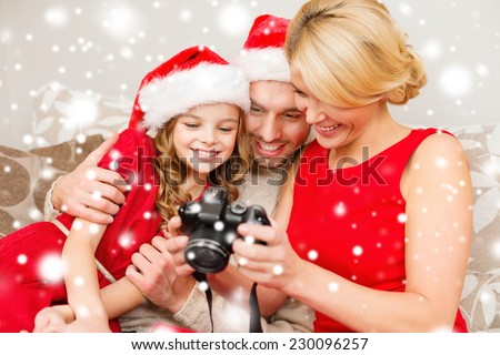 christmas, holidays, technology and people concept - happy family watching photos from digital camera at home