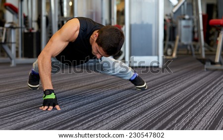 fitness, sport, people and lifestyle concept - man doing one arm push-ups in gym