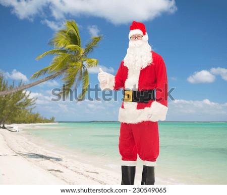 christmas, holidays, gesture, travel and people concept- man in costume of santa claus showing thumbs up over tropical beach background