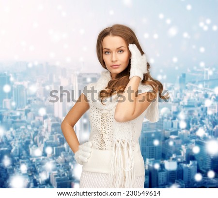 happiness, winter holidays, christmas and people concept - smiling young woman in white warm clothes over snowy city background