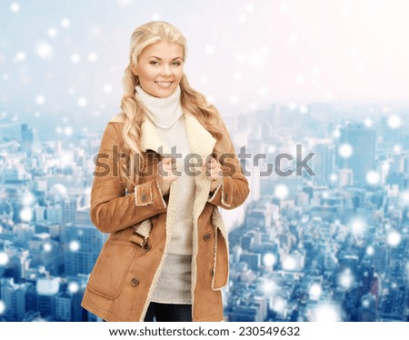winter holidays, christmas, fashion and people concept - smiling young woman in winter clothes over snowy city background