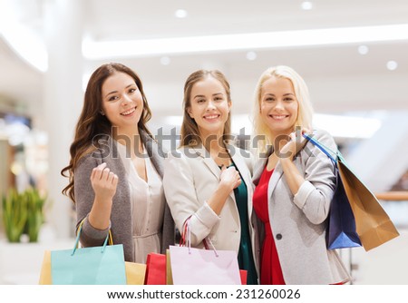 sale, consumerism and people concept - happy young women with shopping bags in mall