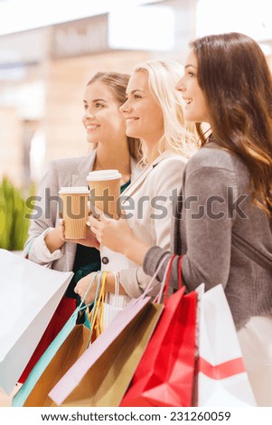 sale, consumerism and people concept - happy young women with shopping bags and coffee paper cup in mall