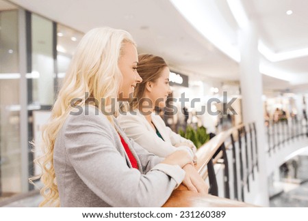 sale, consumerism and people concept - happy young women in mall or business center