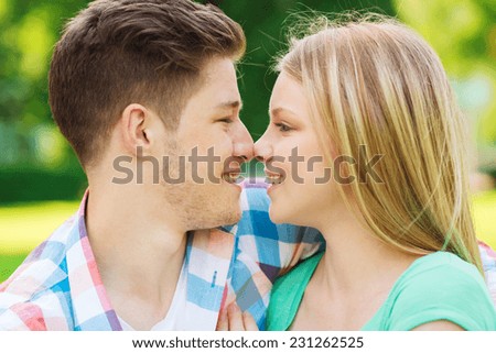 holidays, vacation, love and friendship concept - smiling couple touching noses in park