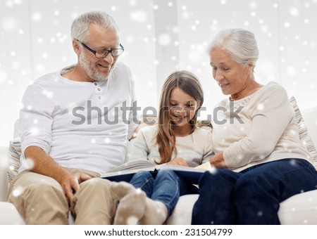 family, generation, education and people concept - smiling grandfather, granddaughter and grandmother with book or photo album sitting on couch at home