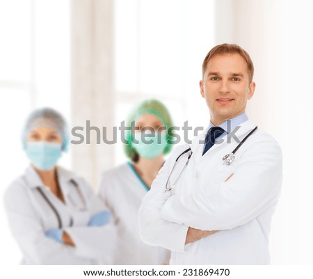 healthcare, profession, teamwork, people and medicine concept - smiling male doctor with stethoscope in white coat over over group of medics