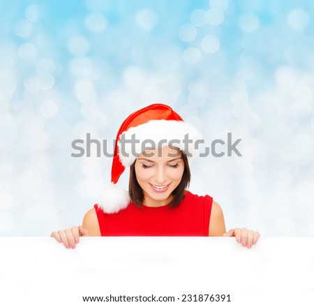 christmas, x-mas, people, advertisement and sale concept - happy woman in santa helper hat with blank white board over blue lights background