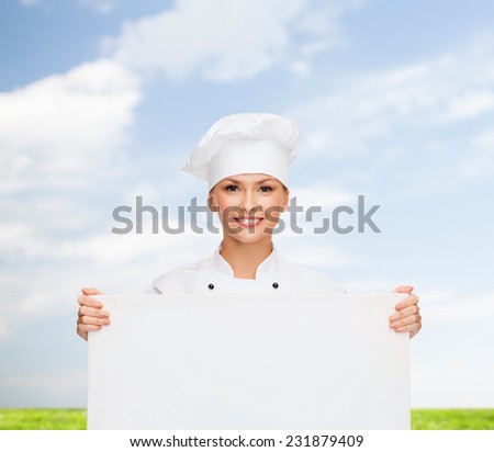cooking, advertisement and people concept - smiling female chef, cook or baker with white blank board over blue sky and grass background