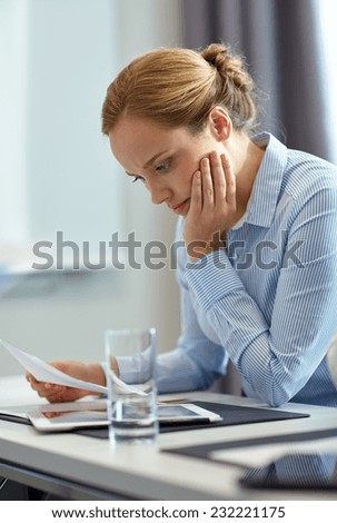 business, people and crisis concept - businesswoman sitting sad and reding document in office