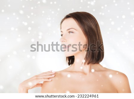 beauty, spa and people concept - beautiful woman with bare shoulders over snowy background