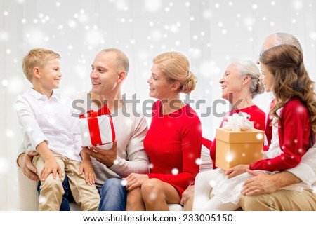 family, holidays, generation, christmas and people concept - smiling family with gift boxes sitting on couch and talking at home