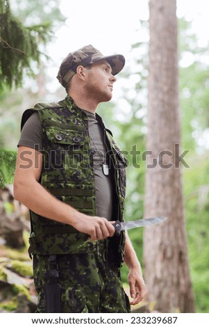 hunting, war, army and people concept - young soldier, ranger or hunter with knife in forest