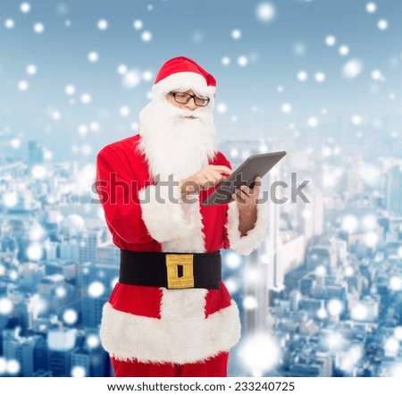 christmas, holidays, technology and people concept - man in costume of santa claus with tablet pc computer over snowy city background
