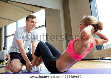 fitness, sport, training, gym and lifestyle concept - woman with personal trainer doing sit ups in gym