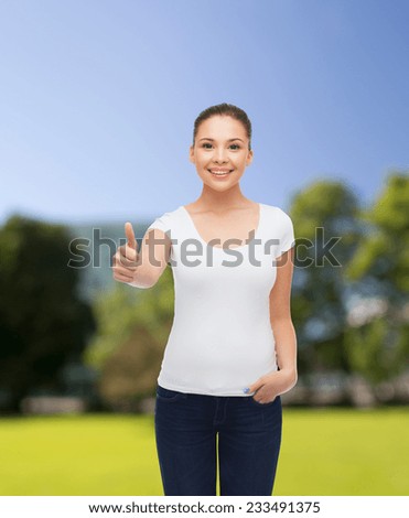advertising, summer vacation, gesture and people concept - smiling young woman in blank white t-shirt showing thumbs up over park background