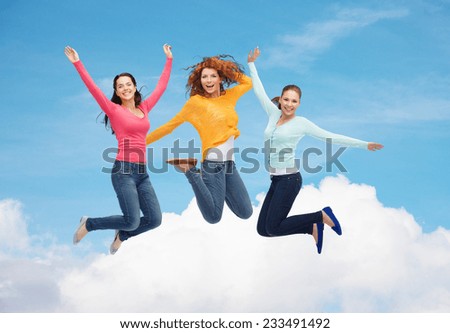 happiness, freedom, friendship, movement and people concept - group of smiling young women jumping in air over blue sky with white cloud background