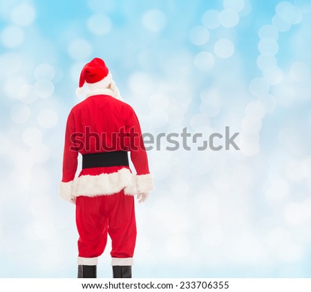 christmas, holidays and people concept - man in costume of santa claus from back over blue lights background