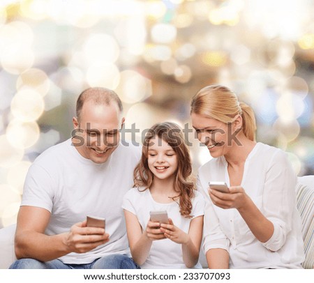 family, holidays, technology and people - smiling mother, father and little girl with smartphones over lights background