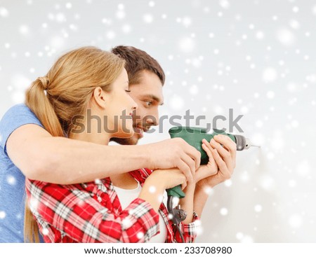 repair, interior design, building, renovation and family concept - smiling couple drilling hole in wall at home