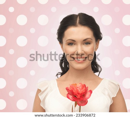 holidays, people and happiness concept - smiling young woman with flower over pink and white polka dots pattern background