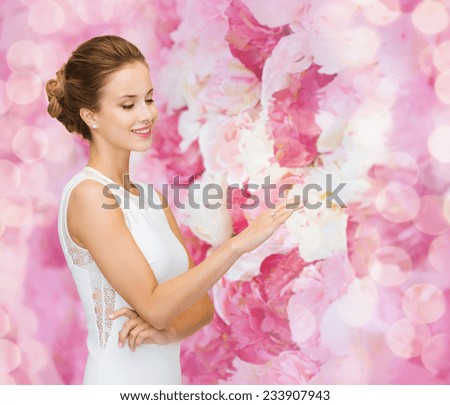 engagement, celebration, wedding and people concept - smiling woman in white dress wearing diamond ring over pink floral background