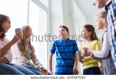 education, elementary school, drinks, children and people concept - group of school kids with soda cans talking in corridor