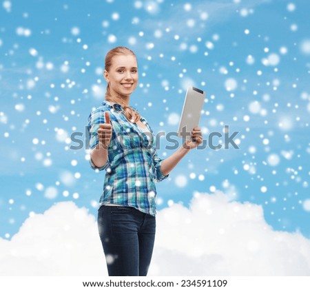 technology, gesture and people concept - smiling girl with tablet pc computer showing thumbs up over blue snowy sky and cloud background