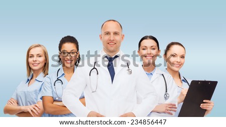 medicine, profession, teamwork and healthcare concept - international group of smiling medics or doctors with clipboard and stethoscopes over blue background