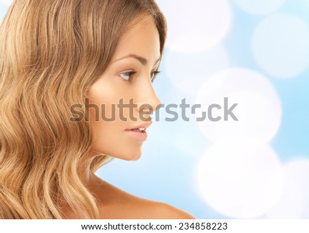 beauty, people and health concept - beautiful young woman face over blue lights background