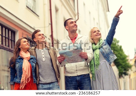 travel, vacation and friendship concept - group of smiling friends with city map exploring city