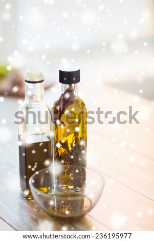 cooking and food concept - close up of two olive oil bottles and glass bowl on wooden table at home kitchen