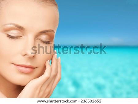 beauty, people, vacation and health concept - beautiful young woman touching her face over blue sea and sky background