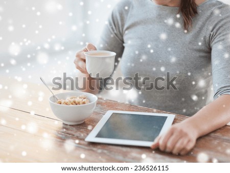 health, technology, food and home concept - close up of woman with to tablet pc computer having breakfast and drinking coffee