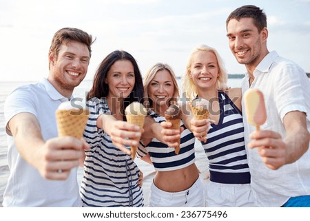 summer, holidays, sea, tourism and people concept - group of smiling friends showing ice cream on beach