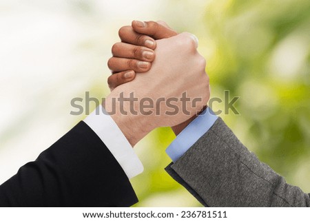 business, people and competition concept - close up of two people hands arm wrestling over green background