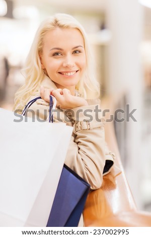 sale, consumerism and people concept - happy young woman with shopping bags in mall