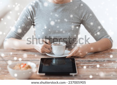 health, technology, internet, food and home concept - close up of woman with to tablet pc computer having breakfast and drinking coffee