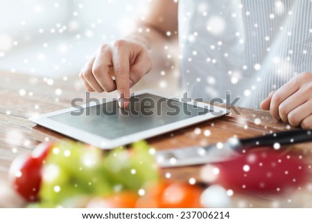 cooking, people, technology and home concept - close up of man reading recipe from tablet pc computer and vegetables on table in kitchen